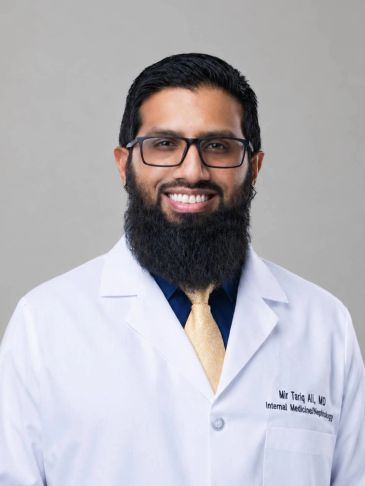 Portrait of a smiling male doctor with glasses and a beard.