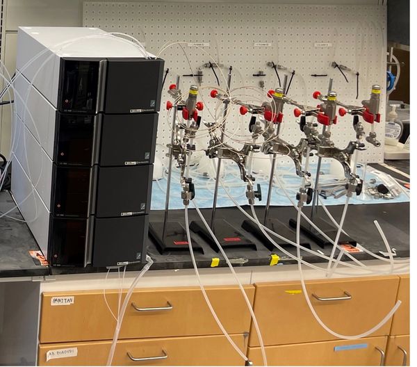 Laboratory liquid chromatography system with connected tubing and flow regulators.