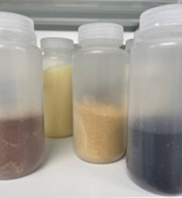 Four plastic containers holding different colored powders and substances.