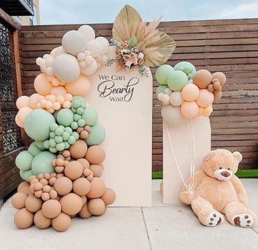 Decorative balloon arrangement with teddy bear and sign saying 'We Can Bearly Wait'.