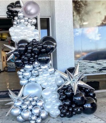 Black, white, and silver balloon arch with star-shaped balloons at an event entry.