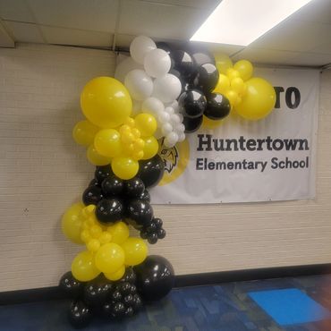 Yellow, black, and white balloon decoration next to a Huntertown Elementary School banner.