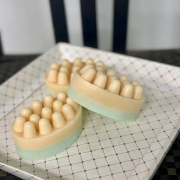 Three round massage soaps with nodules on a patterned tray.