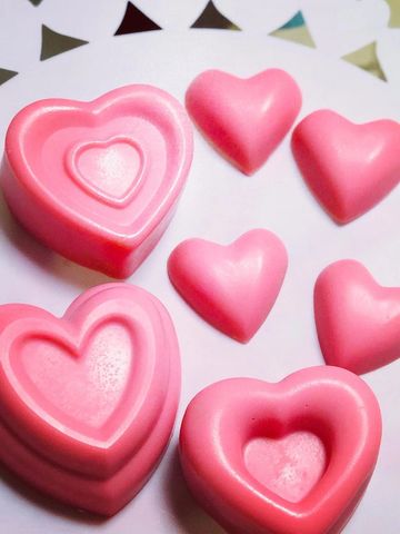 Pink heart-shaped soaps arranged on a white decorative surface.