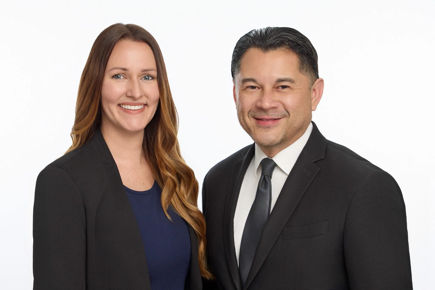 Professional portrait of a smiling man and woman in business attire against a white background.