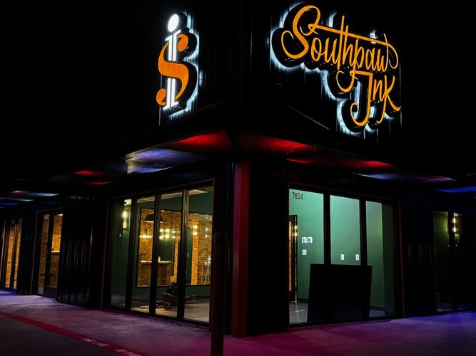 Night view of Southpaw Ink tattoo studio with illuminated signage.