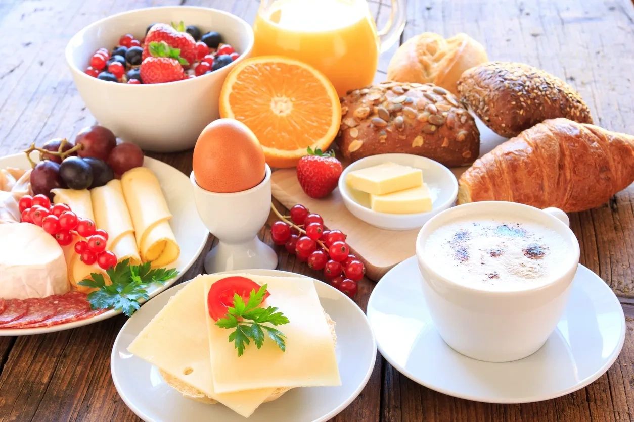 A wholesome breakfast spread with coffee, bread, fruit, cheese, and an egg.