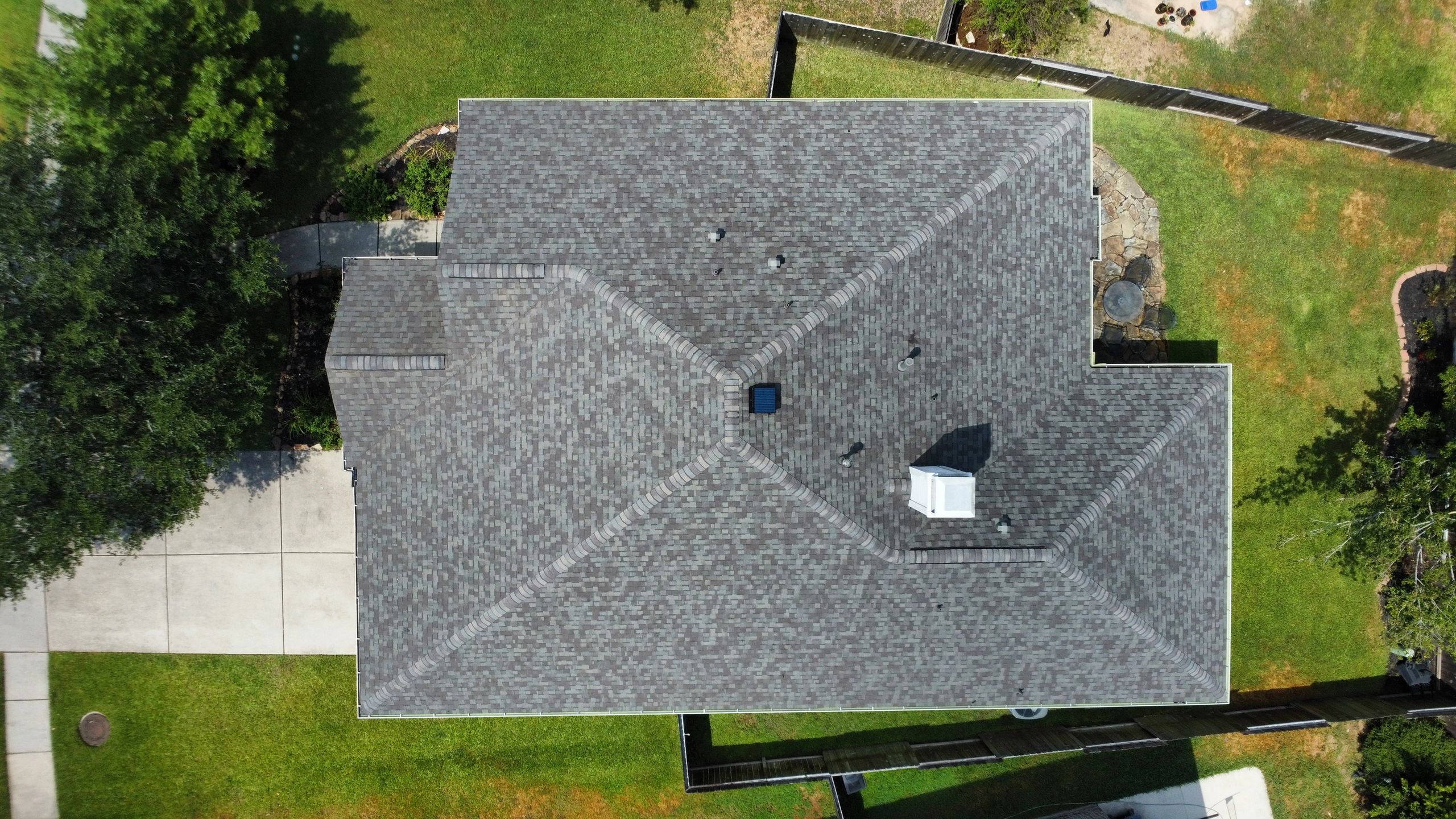 Aerial view of a house roof with a garden and driveway.