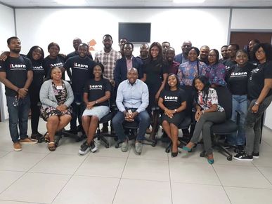 Around 25 people in Nigeria, sitting and standing wearing black Power Platform shirts