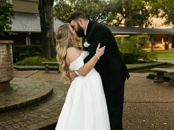 Bride and groom sharing a romantic kiss outdoors on their wedding day.