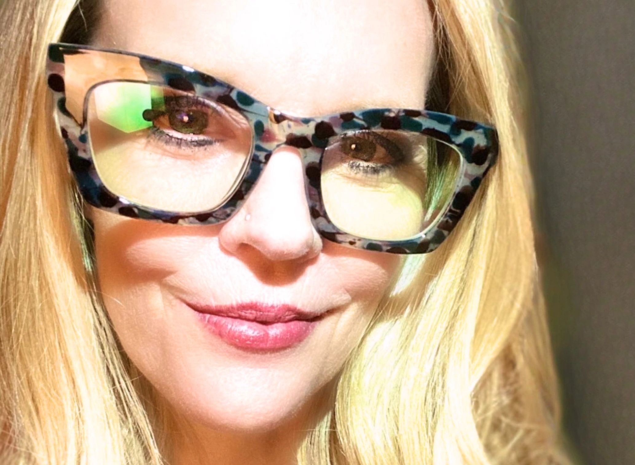 Blond woman with cat shaped eye glasses smiling. She looks like Jenny McCarthy.