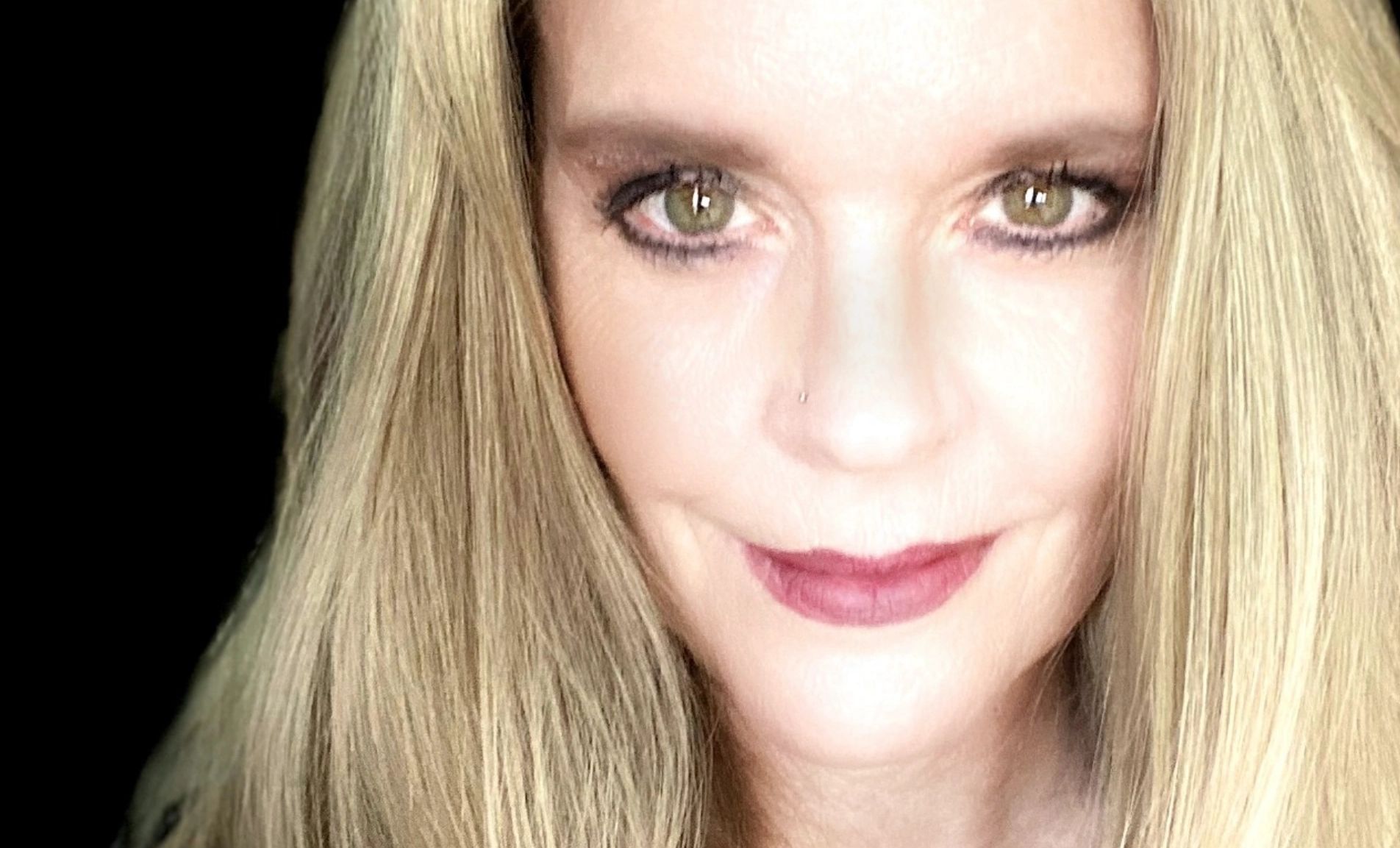 Blond woman with red lipstick looking straight at camera, slight smile