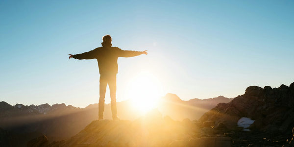Man watching sunset or sunrise, his arms outstretched
