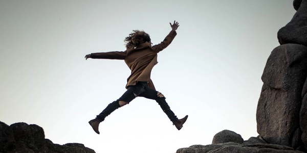 person jumping from one cliff to another