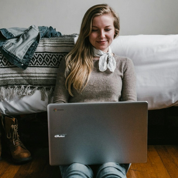Woman sitting on ground reading her laptop computer