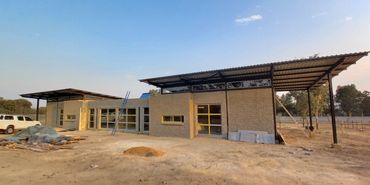 Partially constructed brick building with metal roofing and construction materials around.