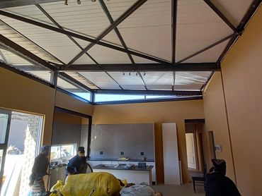 Interior of a room under construction with people working and building materials scattered.