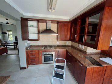 Modern kitchen with wooden cabinets, granite countertops, and a step ladder.