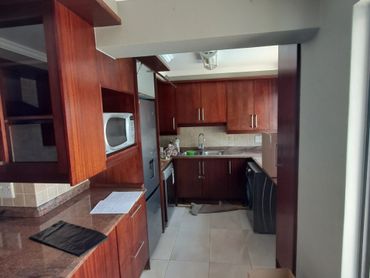 Modern kitchen with wooden cabinets and tiled floor.