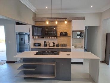 Modern kitchen with island, hanging lights, and built-in appliances.