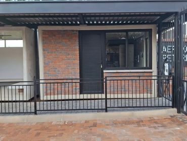 Small brick building with black door and window under metal roof.