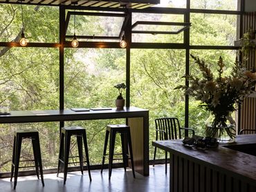 Modern indoor seating area with large windows overlooking lush greenery.