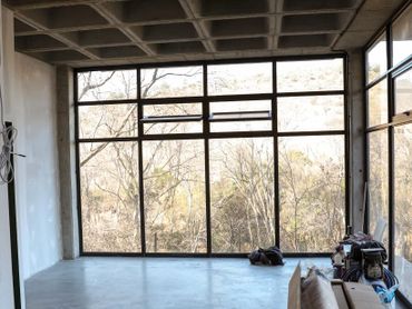 Empty room with large windows and a concrete ceiling under construction.