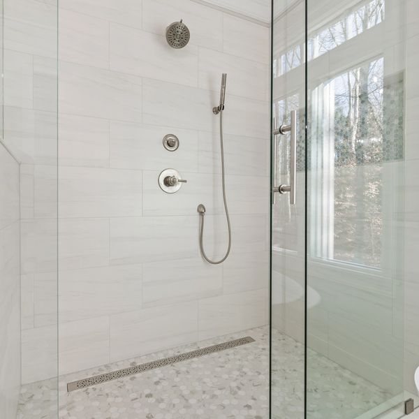 White tiled bathroom shower with glass door in Cumming, GA. Rocky Brook Construction.