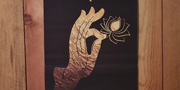 Golden hand holding a lotus flower on a black background.