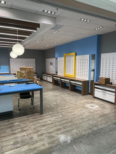 An empty retail space with display shelves, tables, and boxes.