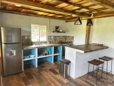 Rustic kitchen with wooden ceiling, tiled counters, and modern appliances.