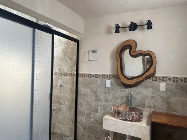 Bathroom with rustic wooden mirror and stone sink.