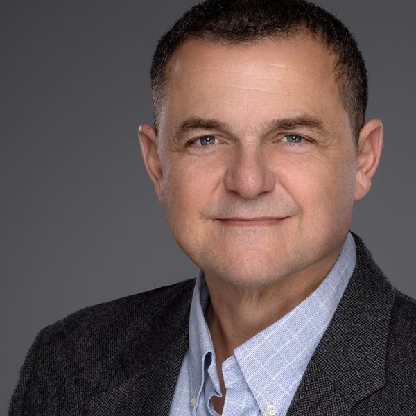 Portrait of a middle-aged man with a friendly expression, wearing a gray blazer and light blue shirt.