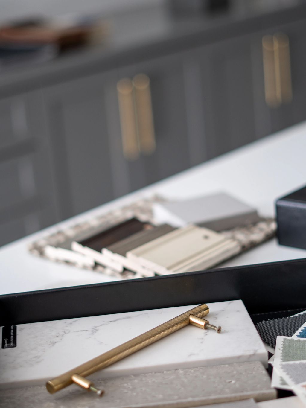Brass cabinet handle resting on marble and tile samples.