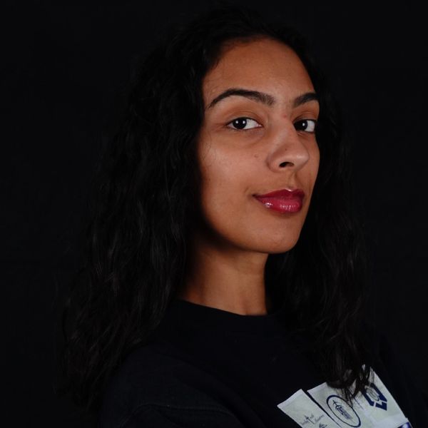 Confident woman with curly hair against a black background.