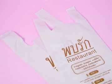 Plastic restaurant bags with Thai text on pink background.