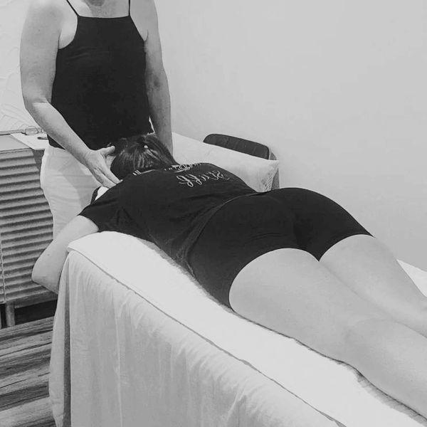 Therapist giving a head massage to a woman lying on a massage table.