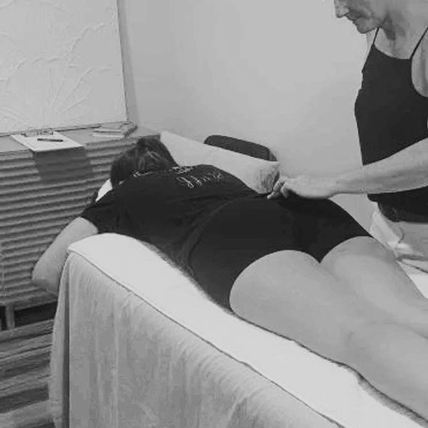 A woman receives a massage while lying on a treatment table.