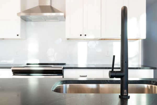 closeup of modern black kitchen faucet with white cabinets