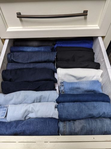 Neatly folded jeans and pants organized in a drawer.