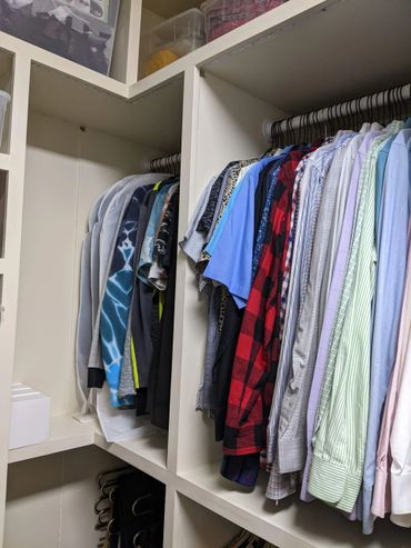 Organized closet with neatly hung shirts and storage boxes.