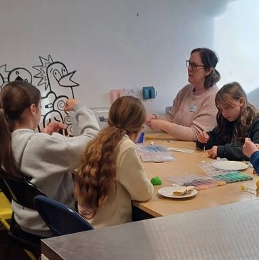 A group of people crafting together at a table with colorful supplies.