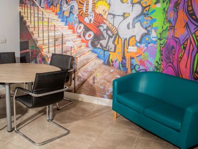 Colorful graffiti wall with modern seating in a casual meeting space.
