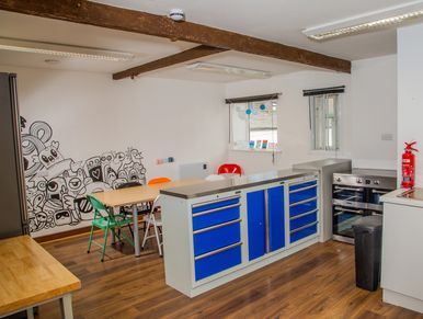 A modern kitchen with blue cabinets and a wooden floor.