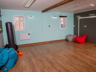 A spacious room with wooden flooring and colorful bean bags.