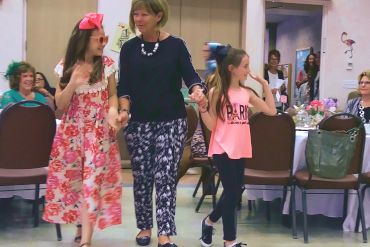 Photo of a member and her two granddaughters modeling outfits at the Mad Hatter Tea and Fashion Show