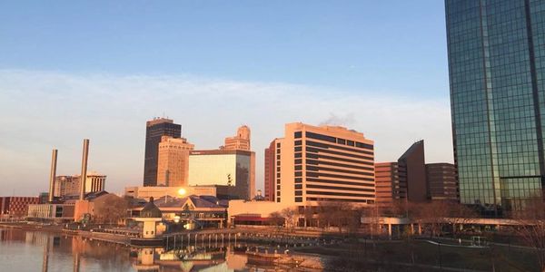 City skyline reflecting on calm river during sunset.