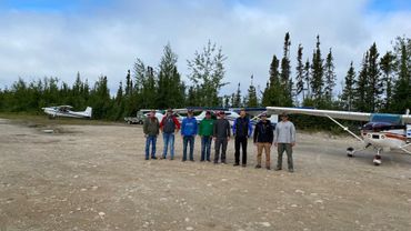 flying club group picture with single engine aircraft parked behind them at Crystal Lodge Cree Lake