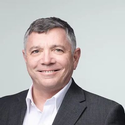 Professional man smiling in a suit against a plain background.