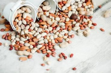Mixed nuts spilled from white containers.